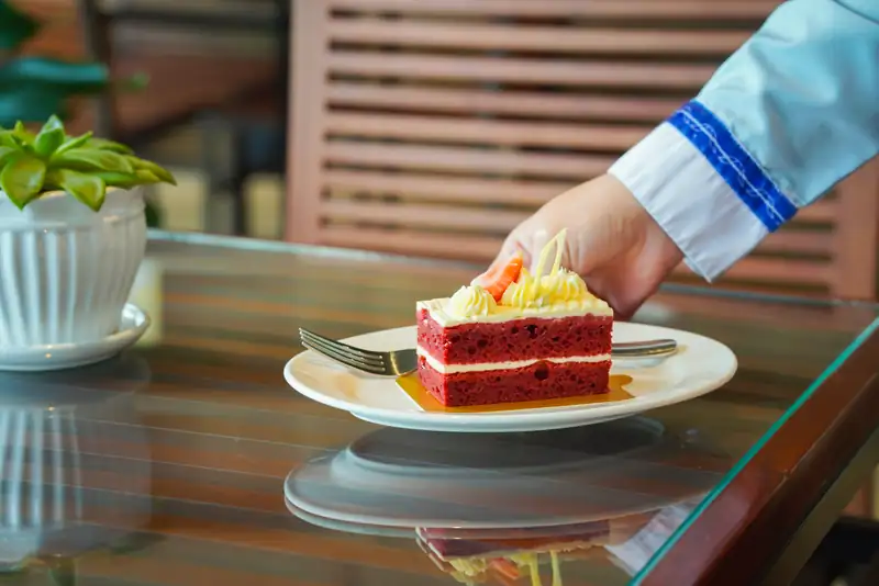 Nhân viên đặt bánh red velvet lên bàn ở Coco Café & Patisserie