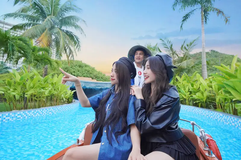 Hai khách ngồi thuyền gỗ có người lái đội nón trên sông Fuji, công viên nước ngoài trời Mikazuki Đà Nẵng