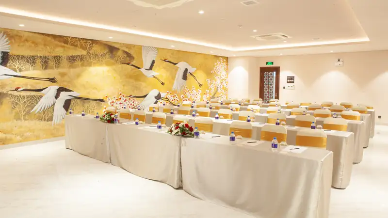 Phòng Hasu Mikazuki Đà Nẵng bày bàn kiểu lớp học cạnh bức tranh tường hạc bay trên nền vàng