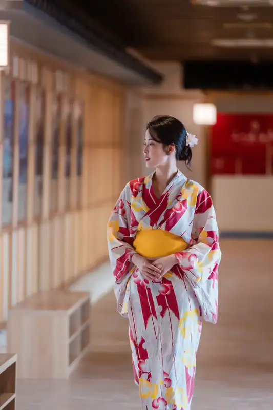 Khách mặc yukata hoa đỏ đứng ở hành lang có dãy tủ gỗ, khu onsen Mikazuki Đà Nẵng