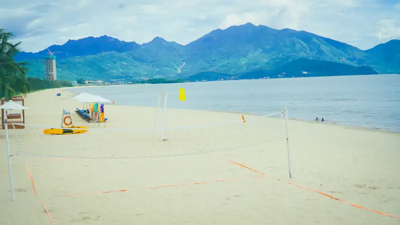 Bãi biển Xuân Thiều của Mikazuki Đà Nẵng có lưới bóng chuyền, phía xa là dãy núi bên vịnh