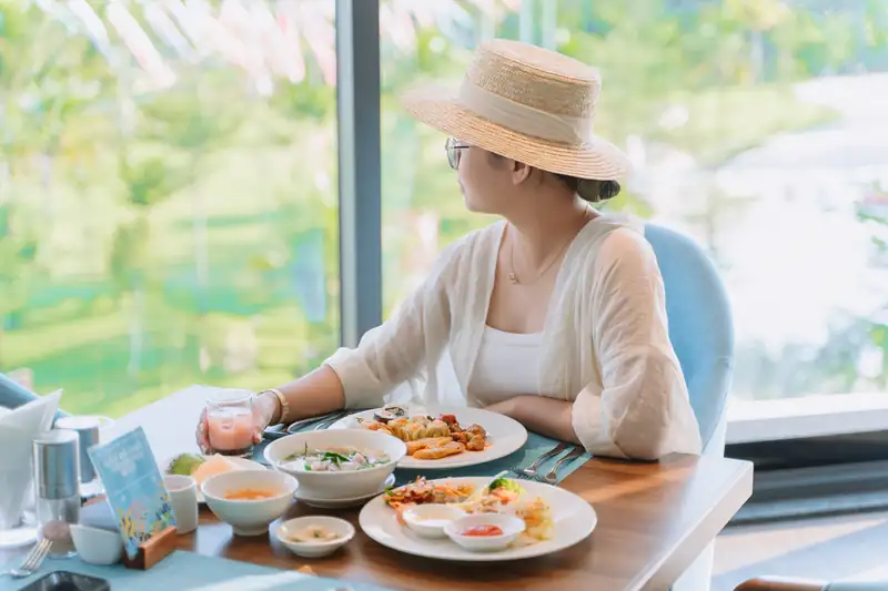 Khách ăn sáng bên cửa kính nhìn ra vườn cây ở nhà hàng The Blue, Mikazuki Đà Nẵng