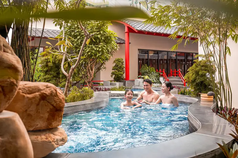 Bố mẹ và con gái ngâm bể onsen tròn ngoài trời cạnh hòn đá và mái ngói đỏ, Mikazuki Đà Nẵng