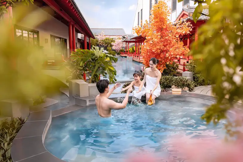 Bố mẹ và con nhỏ té nước trong bể onsen ngoài trời bên cây lá đỏ, Mikazuki Đà Nẵng