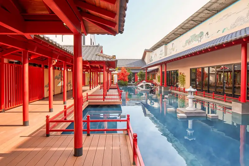 Hành lang gỗ cột đỏ chạy dọc bể onsen dài có đèn đá, Mikazuki Đà Nẵng