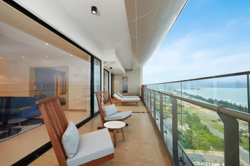 Ban công tầng 21 của Ambassador Suite có ghế tắm nắng, nhìn dọc bờ biển Đà Nẵng