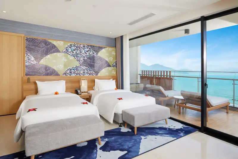 Phòng ngủ hai giường đơn của Ambassador Suite, cửa kính nhìn ra biển