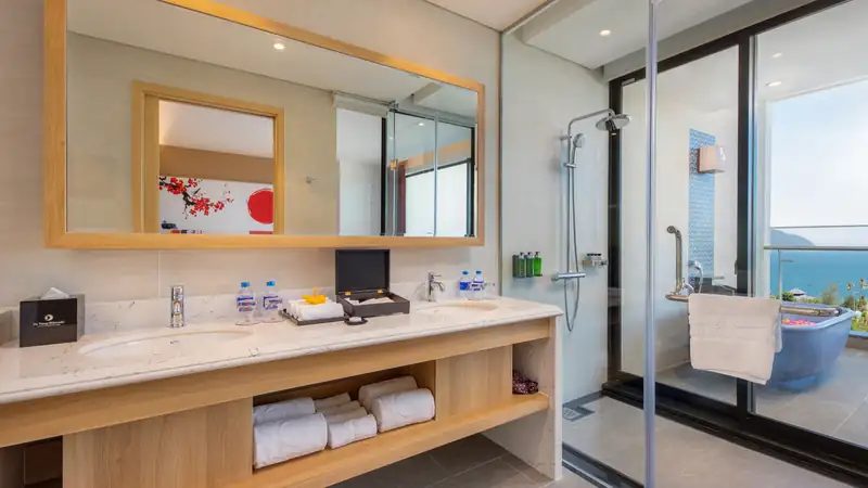 Phòng tắm phòng Family: bồn rửa đôi, buồng tắm kính, phía ngoài là bồn tắm ban công nhìn biển