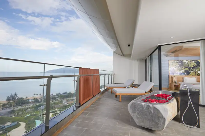 Ban công Presidential Suite có bồn tắm đá và ghế tắm nắng, nhìn ra biển và thành phố