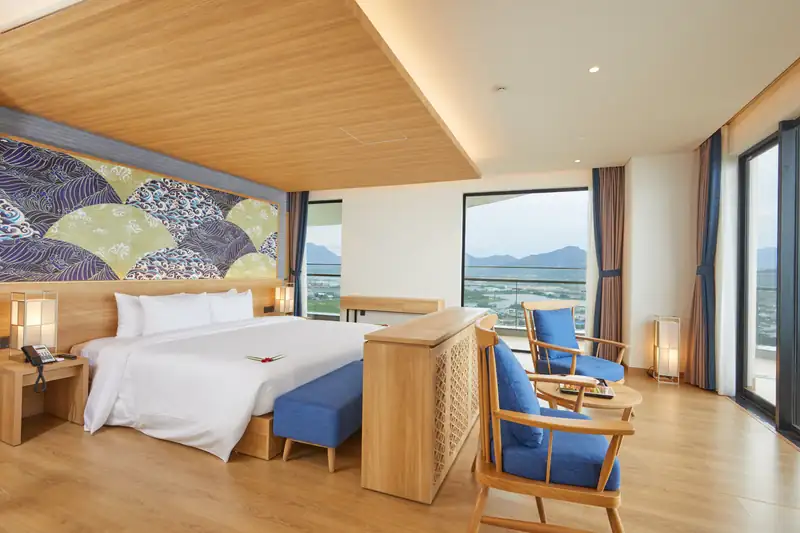 Phòng ngủ giường King có ghế xanh, cửa kính nhìn ra biển, Presidential Suite Mikazuki Đà Nẵng