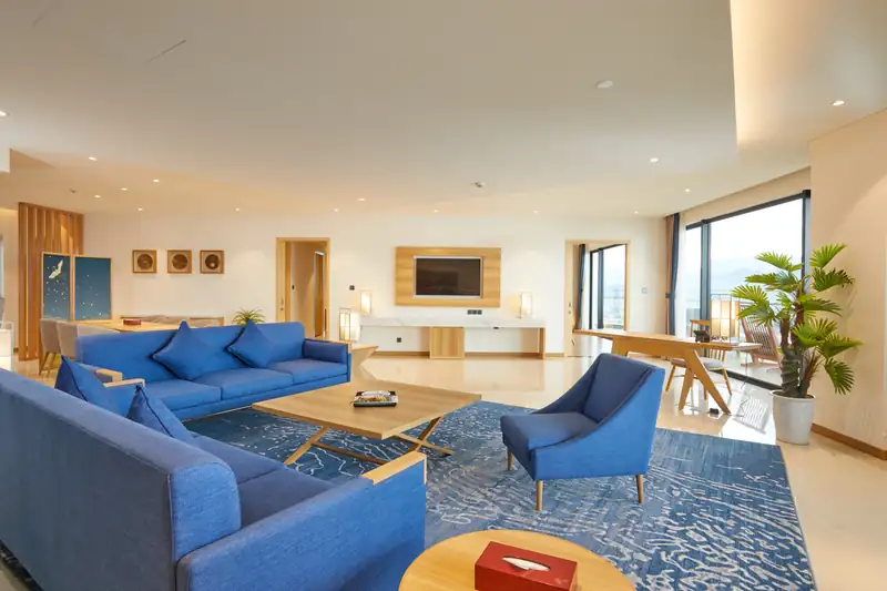 Phòng khách lớn Presidential Suite: hai bộ sofa, bàn làm việc, cửa kính nhìn biển
