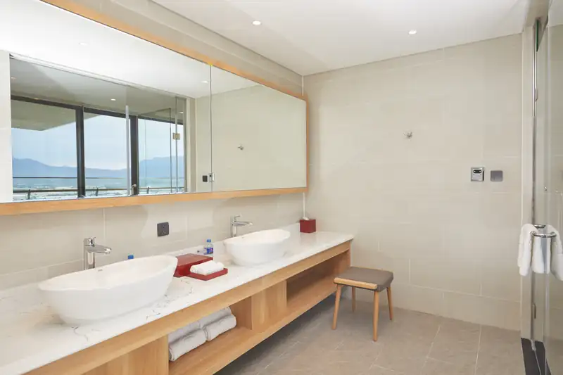 Phòng tắm Presidential Suite: bồn rửa đôi, gương lớn phản chiếu cửa kính nhìn biển
