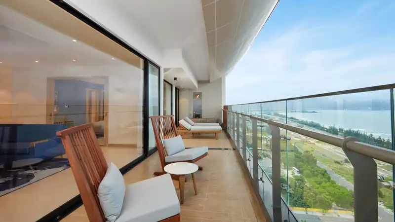 Ban công dài của Senior Suite có ghế tắm nắng, nhìn dọc bờ biển Xuân Thiều, Đà Nẵng