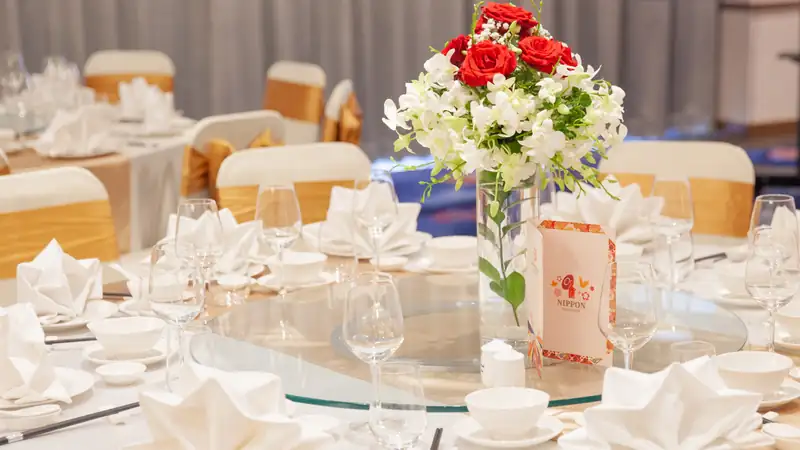 Bàn tiệc tròn bày hoa hồng đỏ, ly và thực đơn in trong phòng Sakura