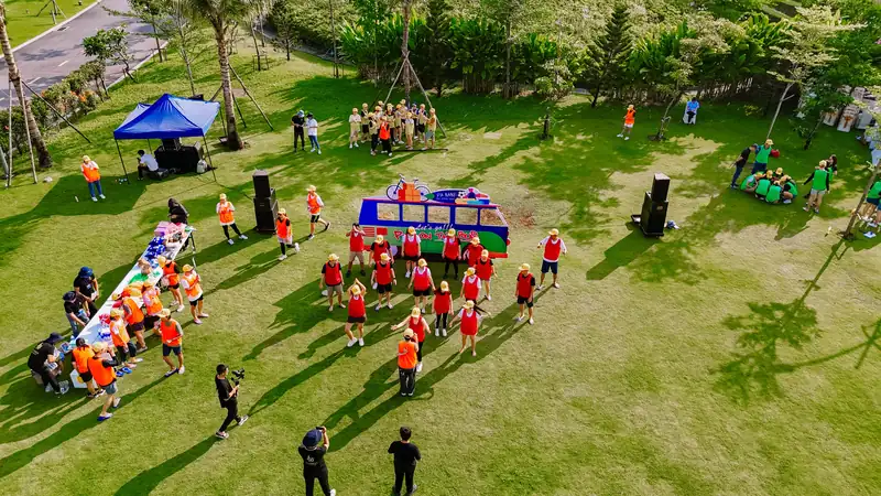 Các đội team building áo đỏ, cam chơi trò chơi trên bãi cỏ khu núi Phú Sĩ, nhìn từ trên cao
